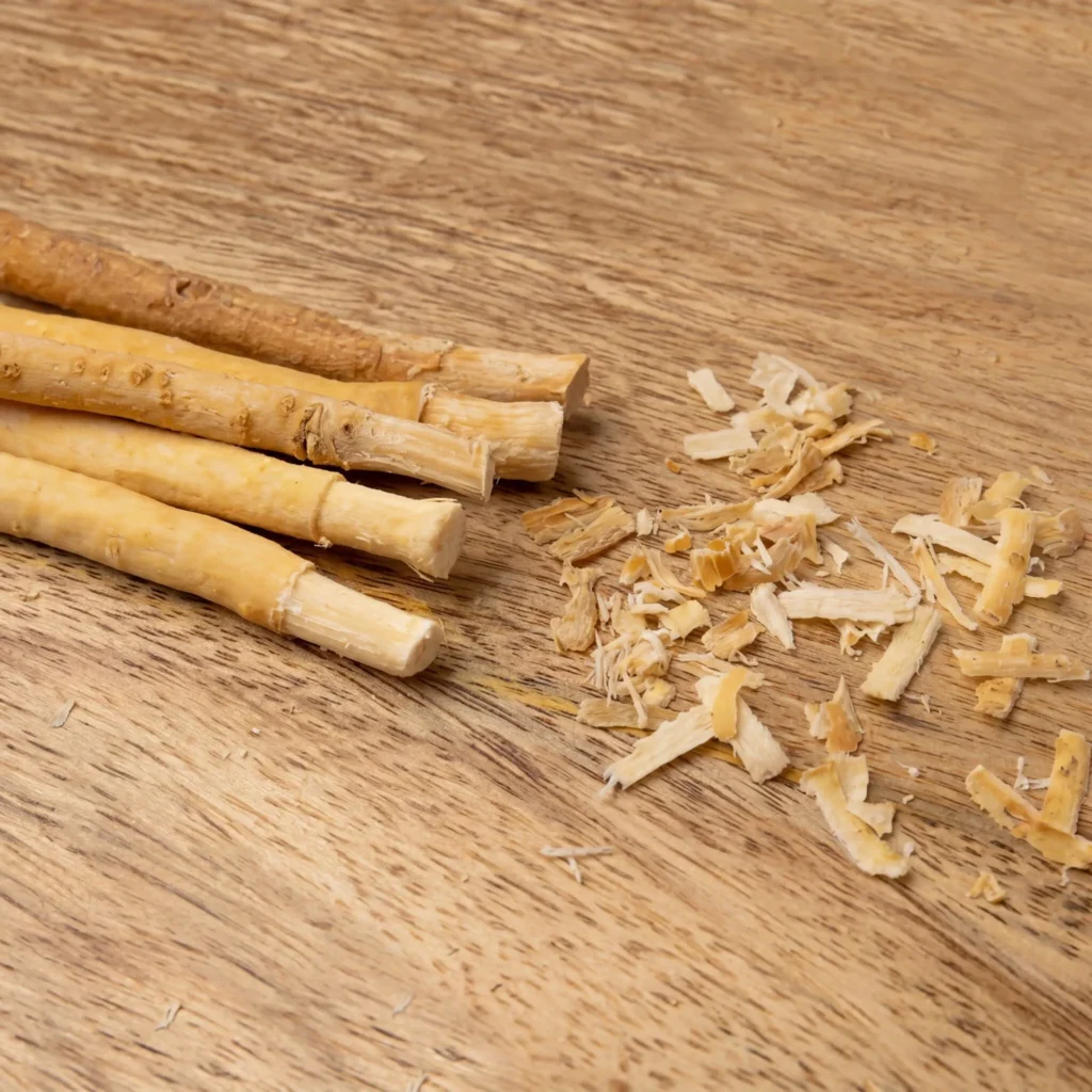 Natural Peelu Miswak sticks with trimmed ends and root shavings on a wooden surface